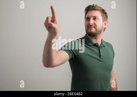 Porträt von seriösen stilvollen attraktiven Mann mit dicken Bart, in lässigen grünen T-Shirt mit Touchscreen isoliert auf grauem Hintergrund mit Kopie s gekleidet Stockfoto