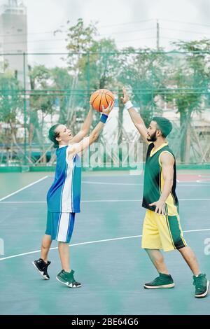 Multi-ethnische junge Menschen spielen Basketball auf Straße Basketballplatz Stockfoto