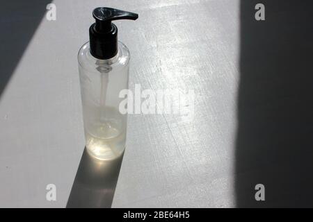 Flasche durchsichtiger Handdesinfektionsmittel auf weißem Holzhintergrund. Antibakterielles Flüssiggel zur Keimprävention und Coronavirus-Prävention. Stockfoto