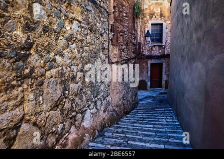 Gasse mit Stufen entlang alter mittelalterlicher Steinmauer in der Altstadt, dem jüdischen Viertel - El Call in der Stadt Girona in Katalonien, Spanien Stockfoto