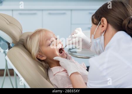 Eine junge Zahnärztin, die eine gründliche Untersuchung der Zähne ihres Patienten durchführt. Stockfoto