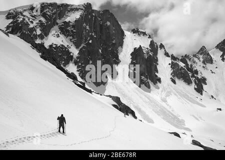 Schneebedeckte Berge mit Lawinenspuren, sonnenbeschienenen Himmel, Wanderer mit Skistöcken und Hund auf verschneiten Hang bei sonnigem Tag. Türkei, Kachkar Berge, Pontic Stockfoto