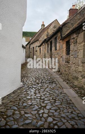 Gepflasterte wynd und Steingebäude entlang der schmalen Gasse im kleinen Dorf des historischen Falkland, Fife, Schottland, Großbritannien, Europa Stockfoto