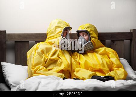 Zwei Personen, die sich im Bett selbst isolieren, sind besonders vorsichtig und tragen einen Hasmatanzug Stockfoto