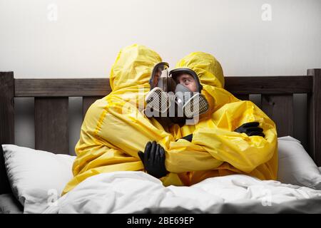 Zwei Personen, die sich im Bett selbst isolieren, sind besonders vorsichtig und tragen einen Hasmatanzug Stockfoto