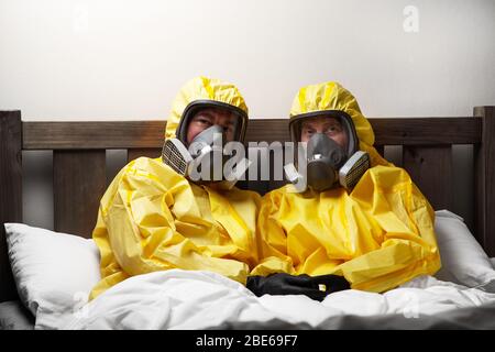 Zwei Personen, die sich im Bett selbst isolieren, sind besonders vorsichtig und tragen einen Hasmatanzug Stockfoto