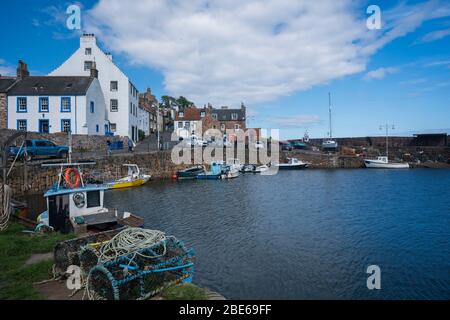 Boote, die an der Pier mit Hummerkäfigen um den Fischerhafen, Crail, Kingdom of Fife, Schottland, Europa gebunden sind Stockfoto