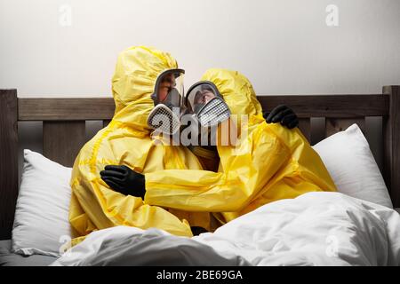 Zwei Personen, die sich im Bett selbst isolieren, sind besonders vorsichtig und tragen einen Hasmatanzug Stockfoto