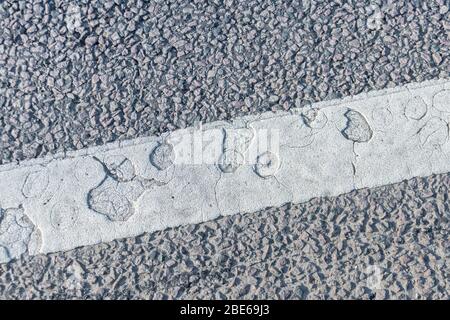Abstraktes gepunktetes Muster in weißer Farbe der Straßenmarkierung in Großbritannien. Alte Farbstruktur, abstrakte Formen, Löcher abstrakt, runde Löcher, Straßentransport Konzept. Stockfoto