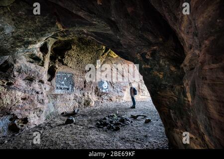 Eine Touristenin erkundet die Caiplie Caves, oder Coves, Felsformationen entlang der Nordsee auf dem Fife Coastal Path, Crail, Schottland, Europa Stockfoto