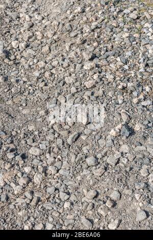 Sonnenbeschienenen Stein / Kies Hardcore auf kleinen Landweg oder Pfad. Metapher fallen auf steinigen Boden, raue Oberfläche, holprigen Boden, raue Fahrt, unebene Oberfläche. Stockfoto