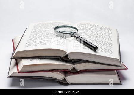 Stillleben von drei offenen Büchern mit einer Lupe auf der Oberseite. Forschung, Entwicklung und Innovation im Kontext von Wissenschaft, Technologie und Gesellschaft Stockfoto