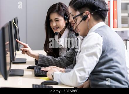Junge Erwachsene freundlich und Selbstvertrauen Betreiber asiatische Mann Agent mit Headsets arbeitet in einem Call-Center mit seinem Kollegen Team als Kundenservice Stockfoto