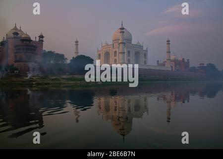 Blick auf den Taj Mahal mit Morgennebel spiegelt sich in den Fluss Yamuna, Agra, Uttar Pradesh, Indien. Taj Mahal wurde als eine UNESCO World Heritage Si bezeichnet. Stockfoto