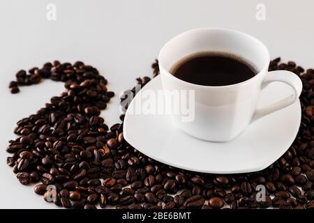 Weiße Tasse mit frisch gegossenem Kaffee Close-up mit Untertasse und Kaffeebohnen herum auf weißem Hintergrund. Toller Hintergrund für ein Café oder Restaurant m Stockfoto