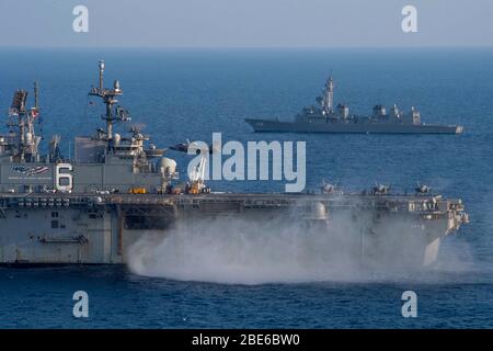 Ein US Marine Corps F-35B Lightning II Stealth Fighter, der 31. Marine Expeditionary Unit zugewiesen, führt eine vertikale Landung auf dem Flugdeck des Flaggschiffs Amerika-Klasse amphibischen Sturmschiff USS America segeln in Formation mit Japan Maritime Self-Defense Force Zerstörer JS Akebono April 10, 2020 im Ostchinesischen Meer. Stockfoto