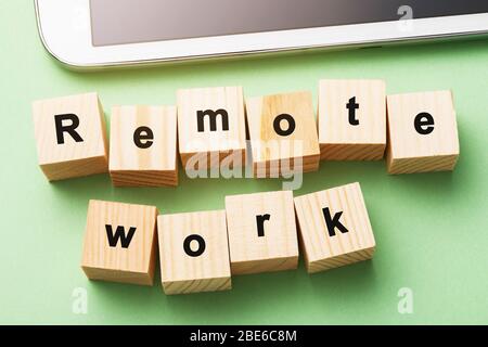 Holzwürfel mit Text und Tafel auf grünem Hintergrund. Remote Work-Konzept Sperren Stockfoto