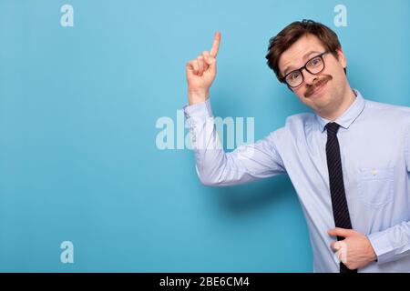 Zufriedener junger Mann in einer Brille, der den Zeigefinger nach oben zeigt, Ratschläge gibt oder Empfehlungen gibt Stockfoto