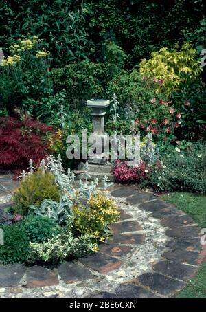 Stachys 'Lanata' und euonymus in kleinen kreisförmigen Bett mit Ziegelstein gepflastert im Garten mit Stein Sonnenuhr eingefasst Stockfoto