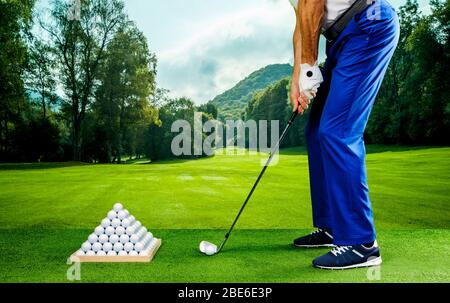 Golfspieler, der in einer Driving Range mit Pyramide von Golfbällen praktiziert Stockfoto