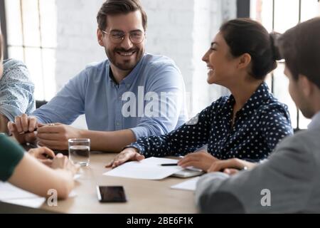 Lächelnde Kollegen aus verschiedenen Rassen lachen über Ideen bei der Besprechung Stockfoto