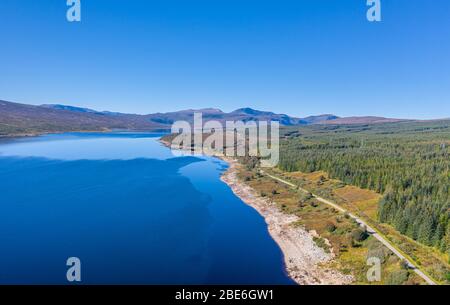 Hoch gelegene Drohnen schießen über Loch Shin entlang der A838 Straße und schauen in Richtung Ben Stack in den North West Highlands of Scotland - NC500 Route Stockfoto