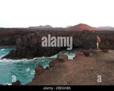 Ein Mann steht auf der Klippe bei Los Hervideros, Timanfaya, vulkanischer Nationalpark, Lanzarote, Kanarische Inseln, Spanien - Januar 2020. Stockfoto