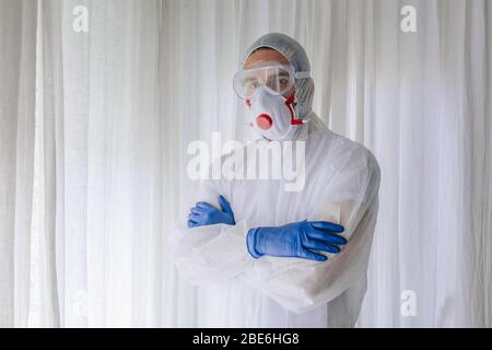 Arzt im Schutzanzug und Gesichtsmaske mit gekreuzten Armen Stockfoto