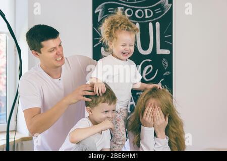 Seine Freizeit verbringt Vater mit seiner Familie. Kinder spielen mit ihren Eltern. Stockfoto