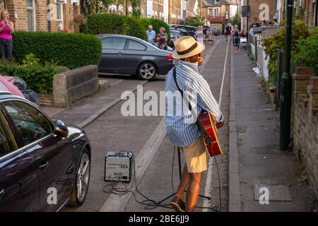 Mann namens D'Artagnan mit Gitarre singt auf der Straße während Covid19 Lockdown Stockfoto