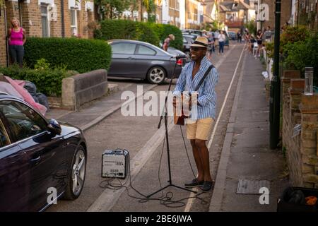 Mann namens D'Artagnan mit Gitarre singt auf der Straße während Covid19 Lockdown Stockfoto