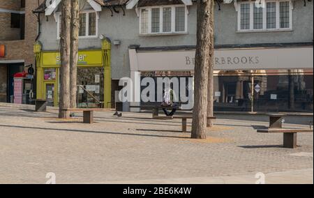 Ein Mann sitzt allein auf einem menschenleeren Bonner Platz, Oxford, Oxfordshire, Großbritannien. Geschäfte und Geschäfte geschlossen wegen der Coronavirus-Pandemie. Stockfoto