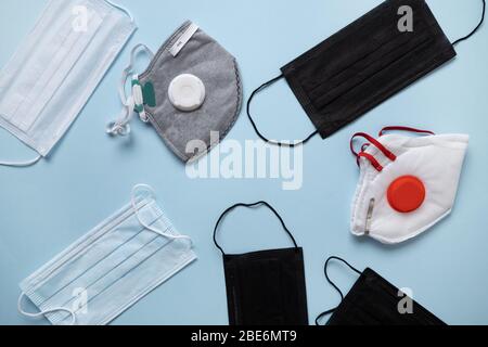 Verschiedene Arten schützende medizinische Gesichtsmaske auf blau. Blick von oben. Prävention von Coronavirus. Stockfoto