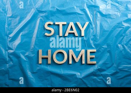 Die Worte bleiben mit silbernen Metallbuchstaben auf zerknittertem blauem Kunststoffhintergrund in flacher Lay-Perspektive, direkt über der Komposition, zu Hause gelegt Stockfoto