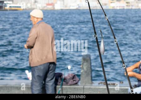 Nahaufnahme von Gusstgewichten, die an der Spitze der Angelrute befestigt sind. Im Hintergrund ist der alte Mann und das Meer. Stockfoto