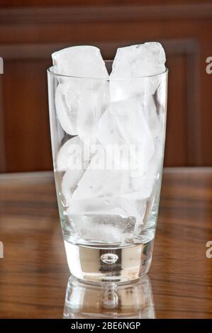 Eisbrocken füllen ein Glas vor dunklem Hintergrund Stockfoto