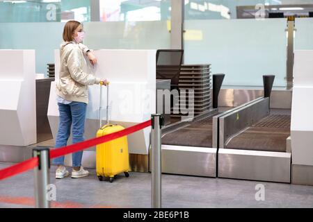 Frau mit Gepäck über Flugannullierung, steht an leeren Check-in-Schaltern am Flughafenterminal wegen Coronavirus-Pandemie/Covid-19-Ausbruch Trave Stockfoto