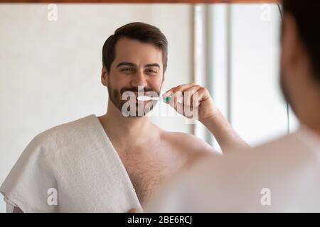 Millennial Kerl genießen tägliche Mundhygiene im Bad. Stockfoto