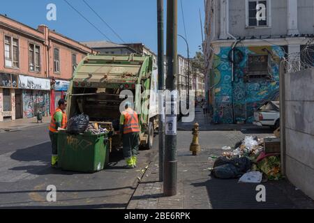 Müllarbeiter sammeln Häuser, während sie Müllcontainer auf den Straßen der Altstadt von Valparaiso, Chile, sammeln Stockfoto