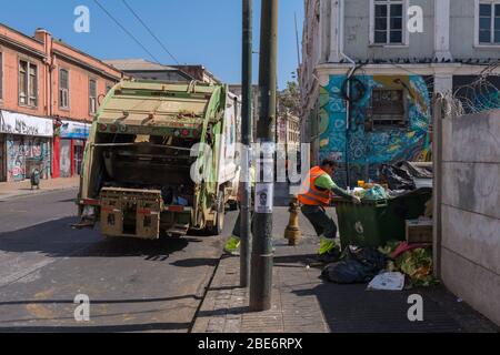 Müllarbeiter sammeln Häuser, während sie Müllcontainer auf den Straßen der Altstadt von Valparaiso, Chile, sammeln Stockfoto