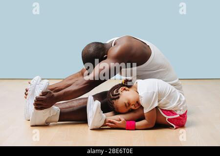 Vater und seine kleine Tochter strecken Knie und Rücken auf dem Boden Stockfoto