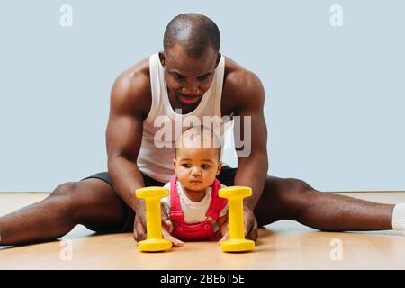 Vater macht körperliche Übungen, während er seine kleine Tochter beobachtet Stockfoto