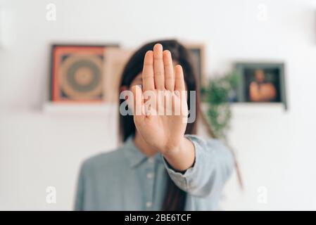 Coronavirus-Konzept. Mädchen in ihrem Haus sagt, Stop mit ihren Händen zu Coronavirus. Globaler Anruf, um zu Hause zu bleiben. Stockfoto