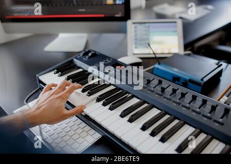 Komponist Hände auf Klavier Tasten im Tonstudio. Musik-Produktion Technologie, Mann arbeitet auf Klavier und Computer-Tastatur auf dem Schreibtisch. Nahaufnahme Stockfoto