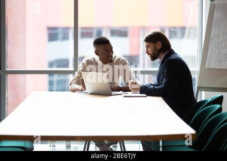 Lächelnd multirassischen Kollegen Brainstorming mit Laptop in der Sitzung Stockfoto