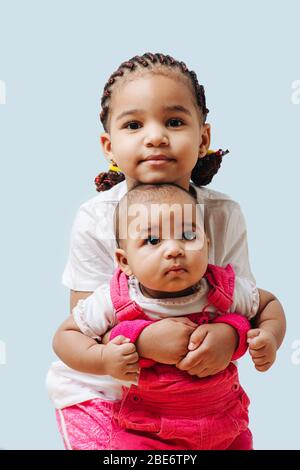 Ältere Schwester hält ihr Kind Geschwister von hinten für ein Foto zusammen Stockfoto