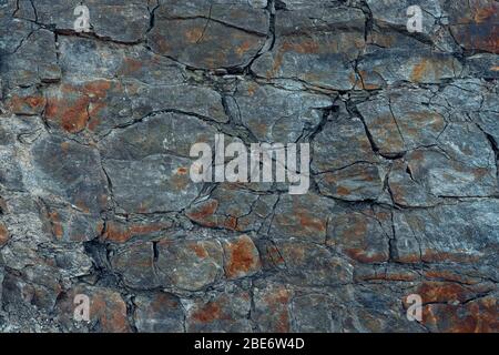 Natürliche Basaltsteinwand mit Rissen und Spalten. Gesteinsstruktur. Graphit Steinwand.Steinhintergrund. Fotografie mit natürlichem Tageslicht. Struktur Stockfoto