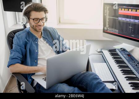 Arbeiten mit einem Laptop. Beschäftigt. Multitasking-Konzept. DJ im Sendestudio. Musikproduzent komponiert einen Song auf Synthesizer-Keyboard und Stockfoto