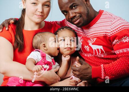 Glückliche Eltern in leuchtend roten Kleidern posieren mit Kindern für ein Familienfoto Stockfoto