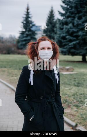 Junges Mädchen trägt ein schützendes Gesicht zu Fuß im Park Stockfoto